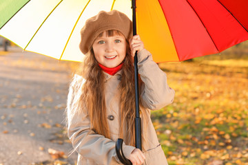 Cute little girl with umbrella in autumn park