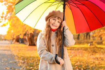 Cute little girl with umbrella in autumn park