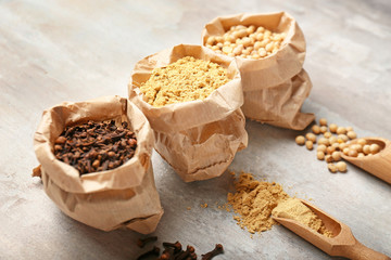 Bags and scoops with spices on light background