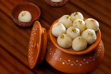 White rasgullas kept in a handi with sprinkled pistachios. 	