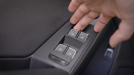 man is pulling lever of power window in automobile to lifting glass, closeup view of hand and finger