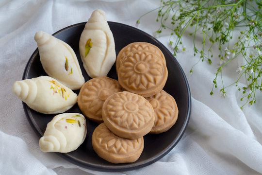 Shankh shaped sondesh and round sondesh kept in a bowl together.	