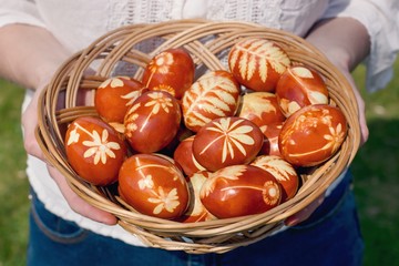 Traditional Easter eggs dyed with natural onion peels and leaves or flowers. Young woman holding basket.