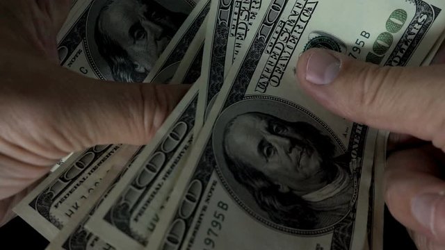 Slow motion of a hand counting of hundred dollar bills.