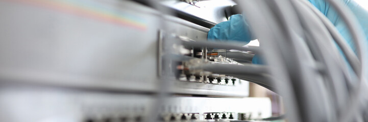 Focus on different internet chords in hand of hardworking man wearing blue glove and plugging...