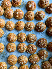 Baked Turkish Homemade Pastry Pogaca with Sesame Seeds on Baking Tray with Sheet Paper.