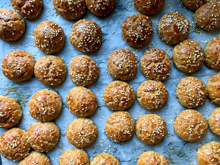 Baked Turkish Homemade Pastry Pogaca with Sesame Seeds on Baking Tray with Sheet Paper.