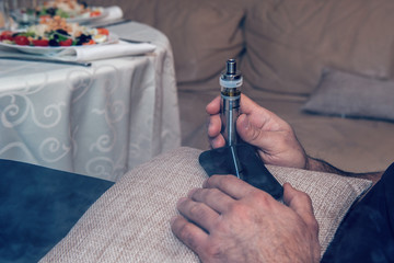 Ban electronic cigarettes. A man holds an electronic cigarette. Harm to health, replacement of cigarettes, provoking cancer and other diseases. Close up