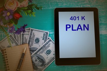 401 K plan in tablet with bank note and book note . business concept.
