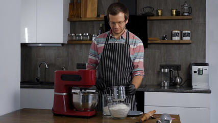 A man cooks in his kitchen. The process of making the dough for later baking. Home