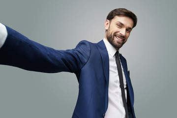 wide angle selfie shot of young handsome stylish businessman wearing suit