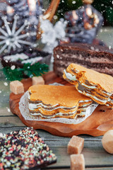 Layer cake lies on the Christmas holiday table. Sweets-sugar, chocolate lie on the wooden surface of the table