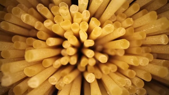 Slowly pulling away from an open bag of spaghetti, high magnification showing great texture of the ends. Revealing the open bag sitting on an upside down pot