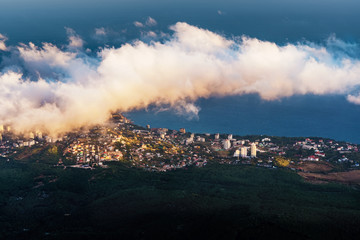 Fototapeta premium A magical view in the mountains above the clouds. Peak AI-Petri in the Crimea in the evening, when the sun sets behind the mountain