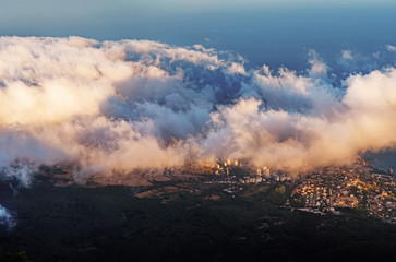 Fototapeta premium A magical view in the mountains above the clouds. Peak AI-Petri in the Crimea in the evening, when the sun sets behind the mountain