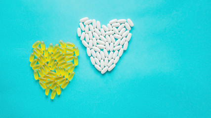 Large medical capsules and tablets-vitamins and food additives on a blue background lie in the shape of a heart. Copy space. Close up. Selective focus