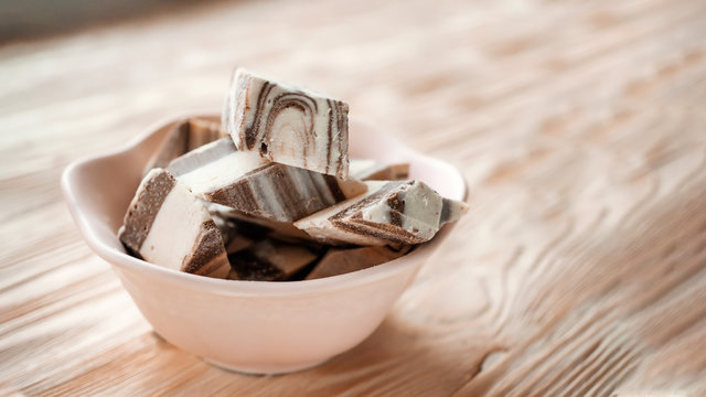 Oriental traditional delicacy-halva sunflower and chocolate in a pink ceramic dish on a wooden background. Festive Oriental delicacy.