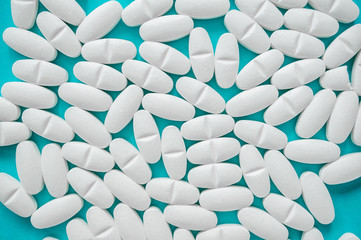 White large tablets are pharmaceuticals for the treatment of various diseases. Close-up, blue background. Selective focus
