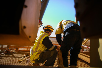 Riggers wearing a fall safety protection helmet are working on final safety check of three tone...