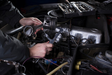 Car engine maintenance. Engine piston system repair. Hands with a mechanic with a caliper measure the size of the piston.