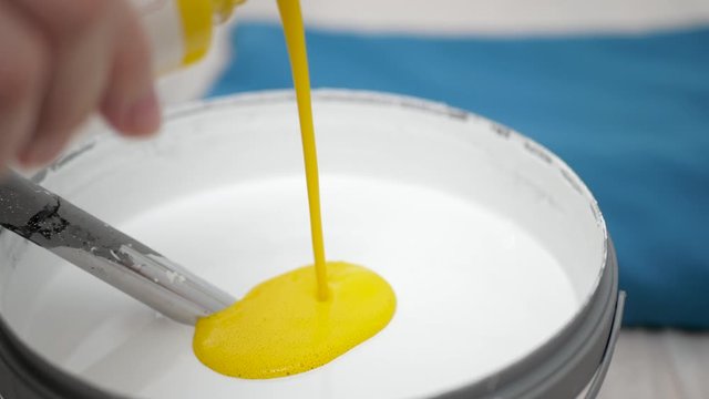 Yellow concentrated color paint is added to white paint. Wall painting concept. Slow motion and close-up view