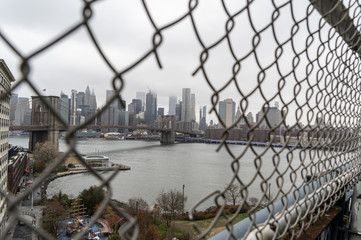 Fence Hole on Manhattan Bridge with downtown Manhattan and Brooklyn bridge on the Background