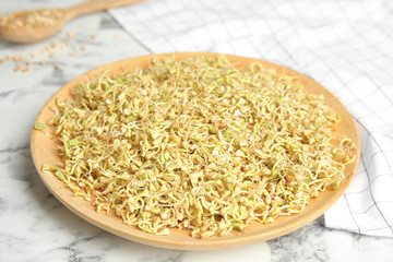 Wooden plate of sprouted green buckwheat on white marble table