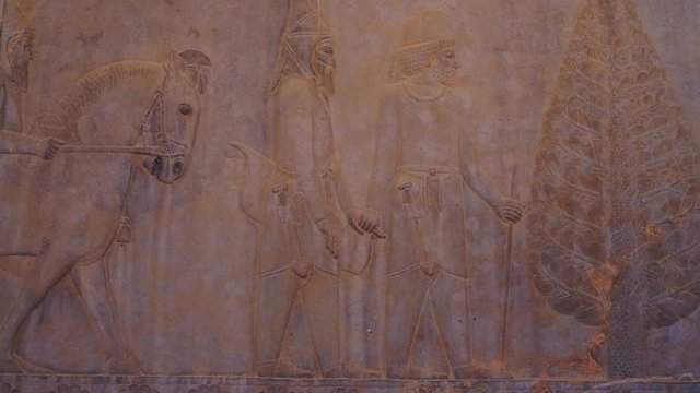 Panning right | People Giving Tributes Relief | Ancient ruins of Persepolis near Shiraz, Southern Iran. This walls's relief shows many things in the past of Persian empire | Silk Road Iran