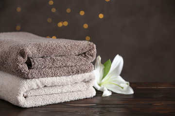 Stack of clean bath towels and beautiful flower on wooden table