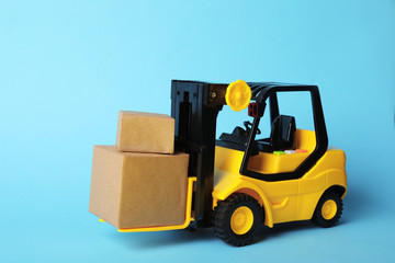 Toy forklift with boxes on blue background. Logistics and wholesale concept