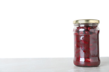 Glass jar of pickled red beans on light marble table. Space for text