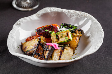 Modern Ukrainian cuisine in the European style. Grilled vegetables, tomato, red onion, eggplant, carrots and zucchini. Edible flowers as a decor. background image, copy space text