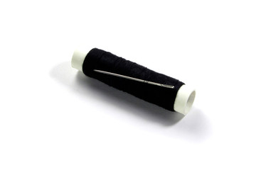 Spool of black thread and needle isolated on a white background.       