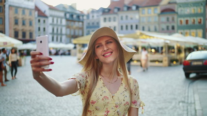 Fototapeta na wymiar Woman taking selfie on square. Attractive woman posing for selfie and standing on city square.