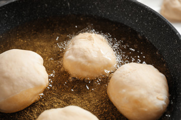 Cooking delicious donuts in hot oil, closeup
