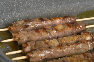 Selective focus. Cooked raw meat skewers is a pan, side view. Close up