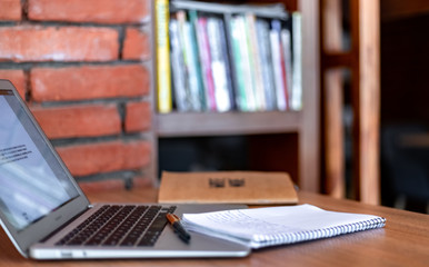 Blogger concept. There is a pc laptop with notebook and pen at a table in a cafe. selective focus