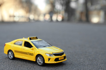 Yellow taxi car model on city street. Space for text