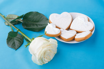 Obraz na płótnie Canvas Heart-shaped cookies and a rose on the blue background, a gift for Valentine's Day