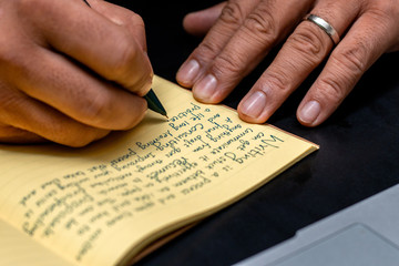 Hand of a young businessman taking notes with a fountain pen on a notecopy.  Student learning online. Blogger. selective focus