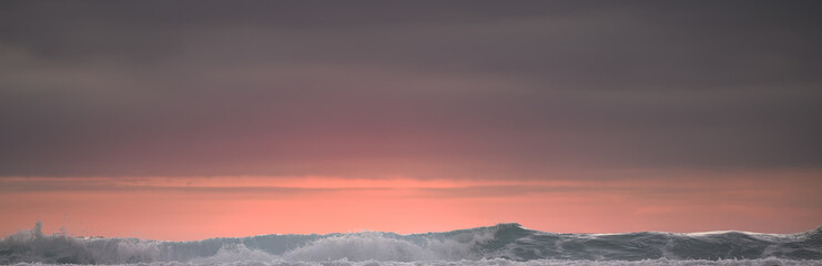 (Selective focus) Stunning view of waves crashing on a beautiful beach during a dramatic and romantic sunset. Lombok Island, West Nusa Tenggara, Indonesia.