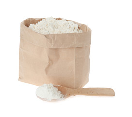 Paper bag and spoon with flour isolated on white