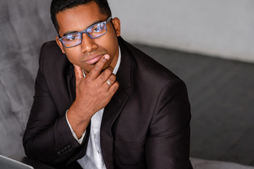 Side view of a successful serious young african american CEO Managing Director in formal clothes working on a new project while sitting at office with a laptop. Managerial position concept