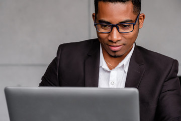 Top view of a successful serious young african american journalist in formal clothes working on a new article while sitting at home with a laptop. Journalism and blogging concept