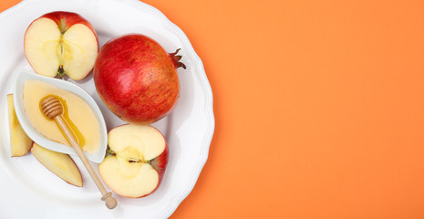 Honey, apples and pomegranate on orange background, top view. with space for text Rosh Hashanah...