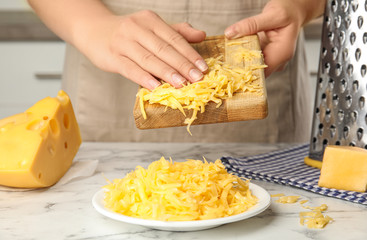 Woman with grated cheese at kitchen table, closeup