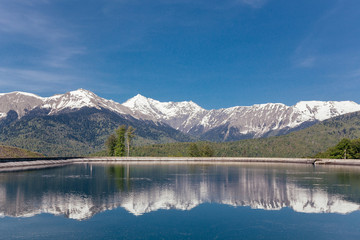 Naklejka na ściany i meble Stunning picturesque landscape of a mountain lake against the backdrop of mountains and blue sky on a sunny warm summer day. The concept of travel and nature reserves. Copyspace