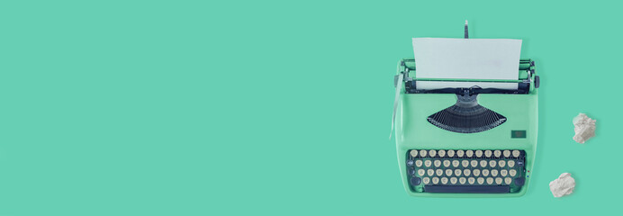 A green vintage typewriter with green background and two paper balls. 