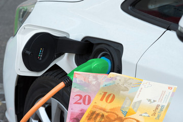 Ein Elektroauto und Geldscheine Schweizer Franken