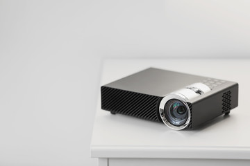 Modern video projector on white table indoors. Space for text
